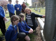 ETCHED IN HISTORY: Classmates look on as Lily Beal and Megan Jones, from Ings Farm School, in Redcar, are shown details of a war grave in Redcar Cemetery by local historian Janet Philo