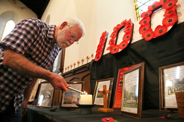 FLAME TRIBUTE: Church volunteer Ian Wood lights a candle at the exhibition at St John’s Church in Darlington. Picture: ANDY LAMB